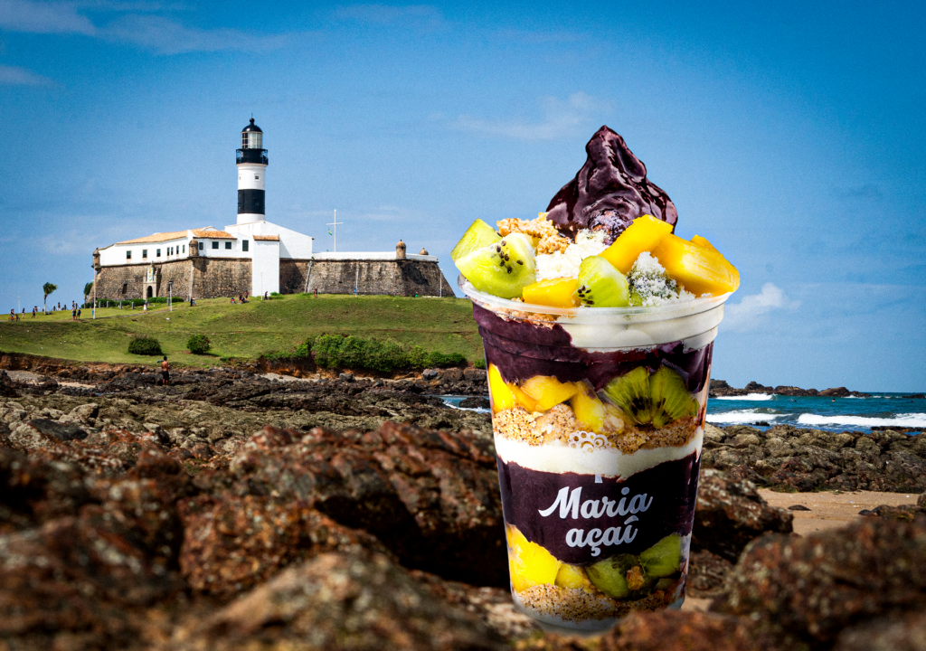 Copo de açaí artesanal na praia, ao entardecer, com o mar ao fundo